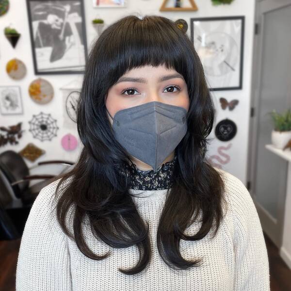 Modern Shag with Crop Styled Fringe - a woman wearing a face mask