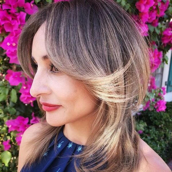 Blonde Balayage with Feathered Bangs - A woman wearing a blue sexy top