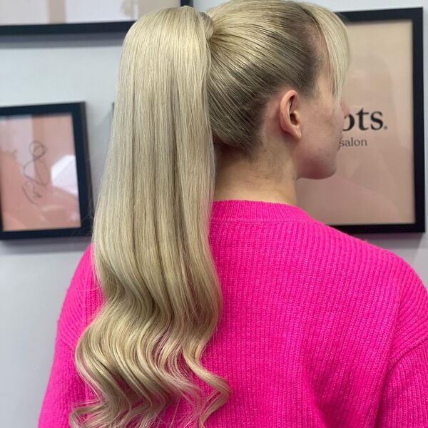 Blonde and Wavy Ponytail with Hair Extensions - A woman wearing a pink sweater