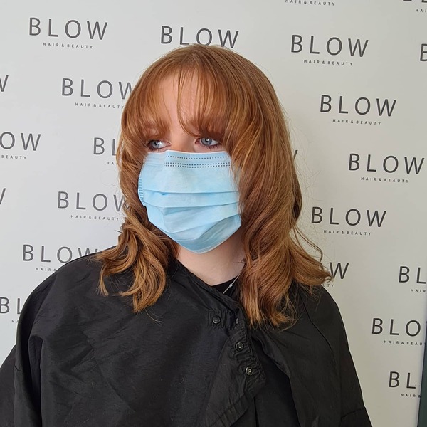 Choppy Feathered Layers Haircut with Bangs - A woman wearing a surgical facemask and black cape