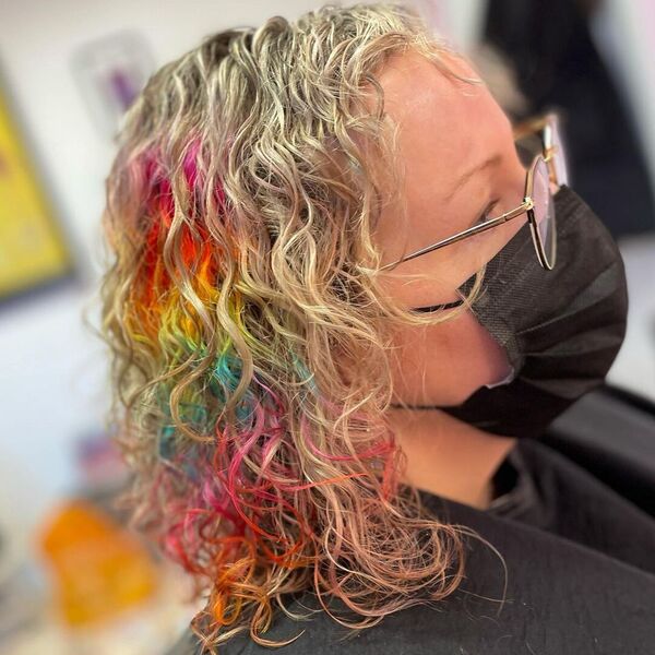 Curly Hidden Rainbow Hair - A woman with eyeglasses wearing a black facemask and black cape