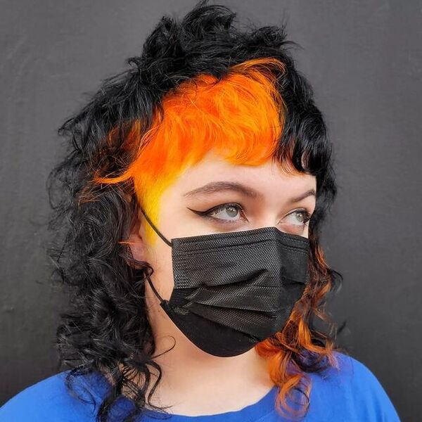 Curly Mullet With Fiery Orange Color - a woman wearing a black face mask