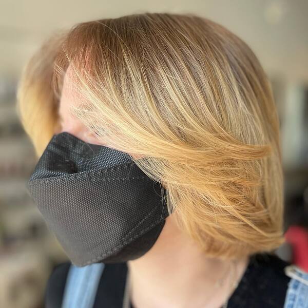 Blonde Hair Color - A woman wearing a black facemask