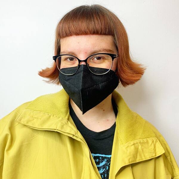 Flippy Bob with Crop Fringe Bangs - a woman wearing a black face mask