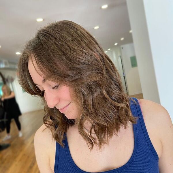 Flowy Layers and Curtain Bangs for Wavy Hair - a woman wearing a sleeveless
