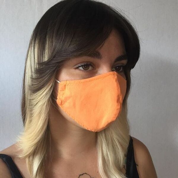Medium-Length Feathered Layered Hair - A woman wearing a orange facemask