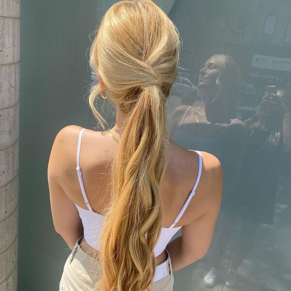 Messy Long Hair Wrap Ponytail Updo - A woman wearing a white sexy crop top