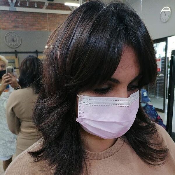 Shaggy Chic Feathered Haircut - A woman wearing a pink facemask