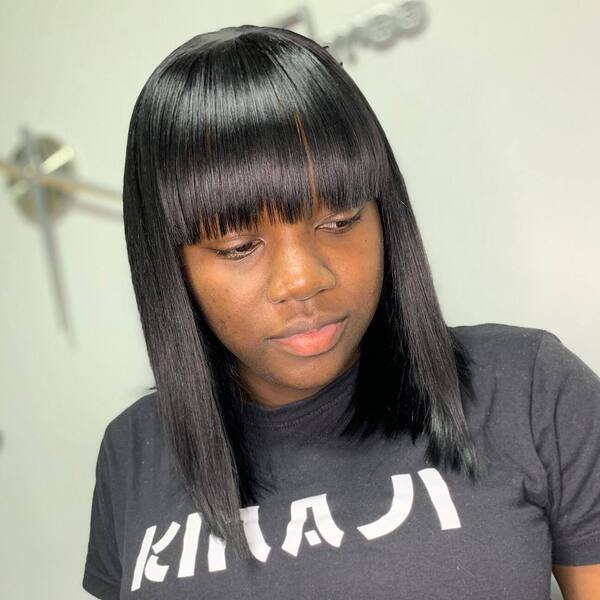 Black Hair in Bob Cut with Blunt Bangs - a woman wearing a black dress