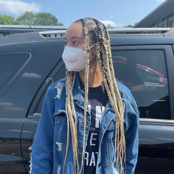 Blonde Knotless Braids - a woman wearing a white face mask