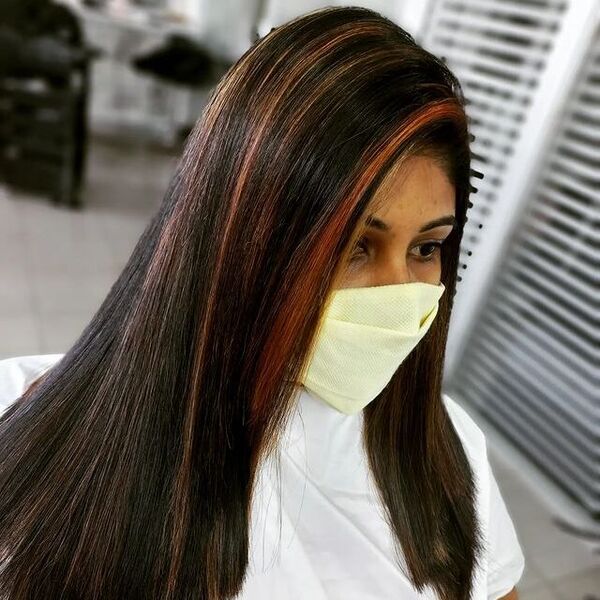 Copper Highlights on Black Hair - a woman wearing a face mask