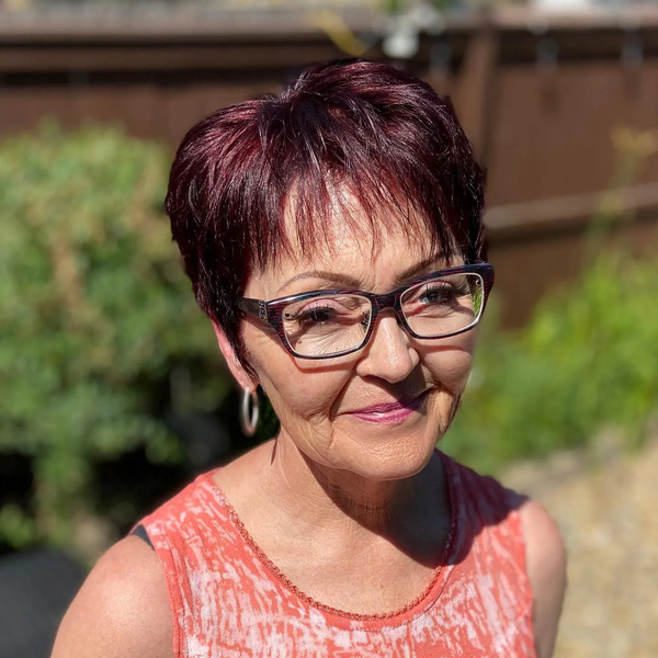 Pixie Cut and Spunky Red with Chopped Bangs - a woman wearing an eyeglasses