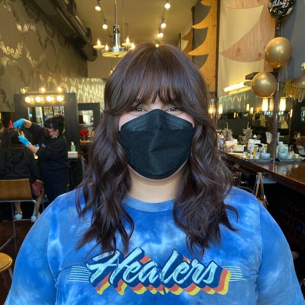 Wavy Brown Hair with Choppy Bangs - a woman wearing a face mask