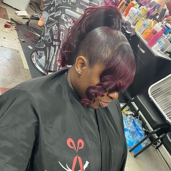 Burgundy Curled Ponytail and Bangs - a woman wearing salon cape