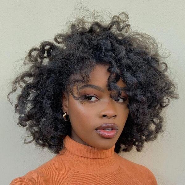 Messy Tight Curl Bob - a woman wearing orang turtle neck