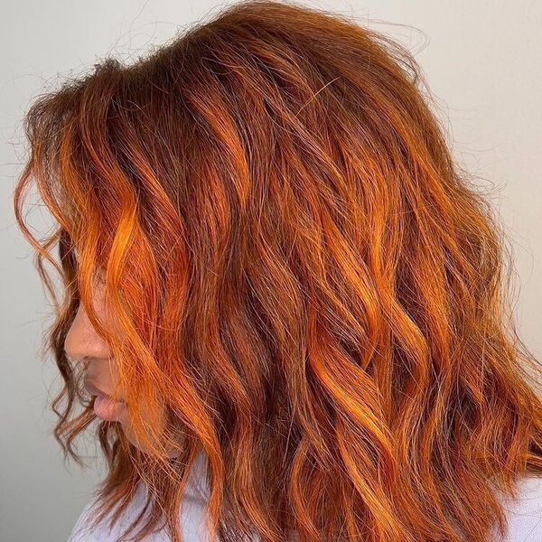 Soft Curls with Bright Orange Balayage- a woman wearing purple top