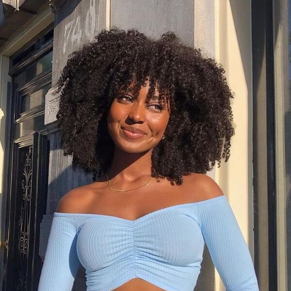 Voluminous Kinky Bob with Bangs - a woman wearing blue crop long sleeves