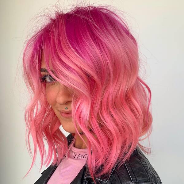 A woman wearing pink shirt underneath denim jacket