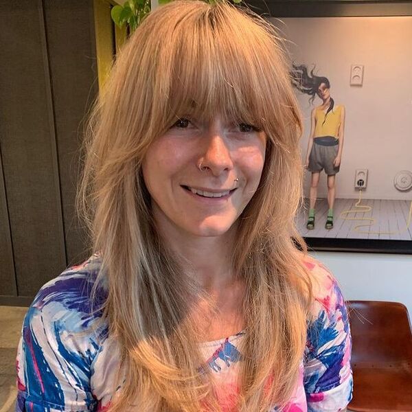 Strawberry Blonde Curtain Fringe and Hairstyle - a woman wearing blue printed top