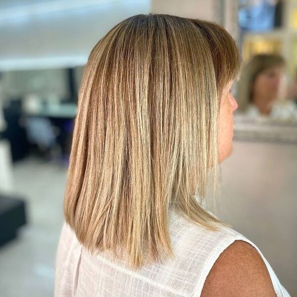 Warm Blonde Long Bob with Short Bangs - a woman wearing white polo